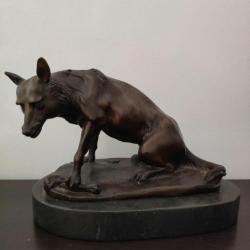 Sculpture en bronze sur socle d'un loup solitaire protégeant son os très bon état.